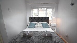 A neatly made bed with a grey headboard, two pillows, and a grey blanket. - Milton Keynes Close to Station 6 bed Free Parking (Milton Keynes)
