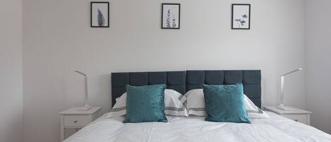 A neatly arranged bedroom with a large bed, two bedside tables, and three framed pictures on the wall.