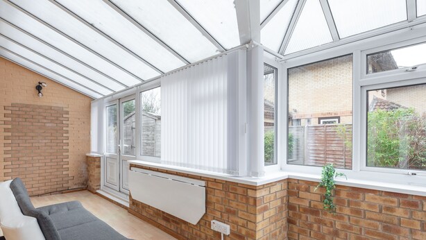 A sunroom with a glass ceiling, brick walls, a radiator, and a window with a plant. - Milton Keynes Close to Station 6 bed Free Parking (Milton Keynes)