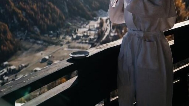 Una persona de pie sobre un puente con vistas a un paisaje montañoso.