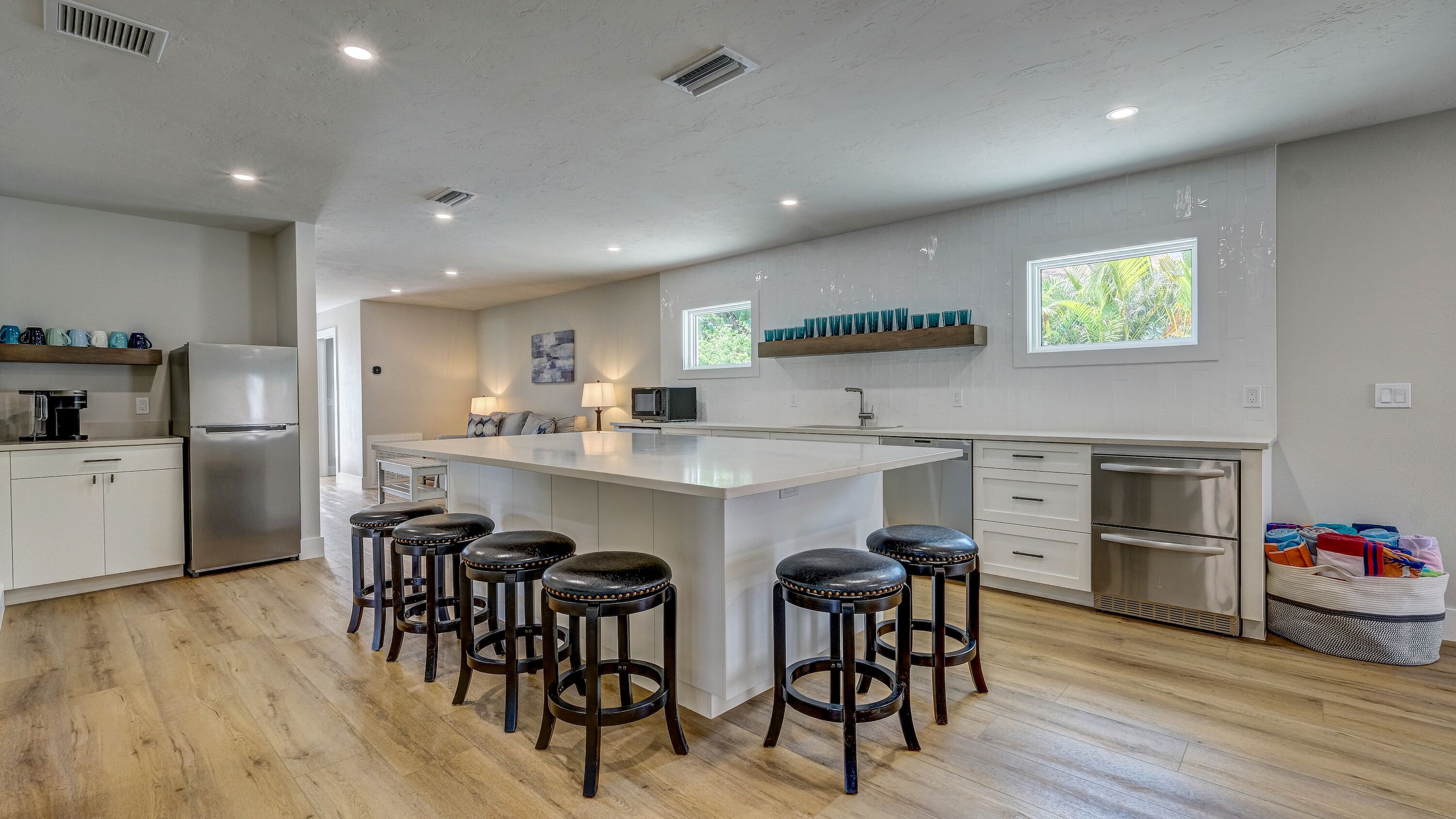 Una cocina moderna con una isla central, taburetes de bar, un refrigerador y un microondas.