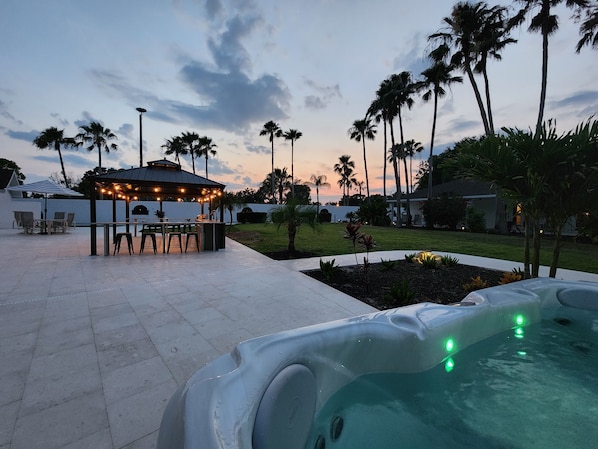 An outdoor patio area with a hot tub, a gazebo with string lights, and palm trees. - ⚓Sleeps 23! 2 Houses on 1 Acre, Min to AMI Beaches!⚓⛳ (Bradenton)