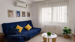A living room with a blue sofa, a round coffee table, and a large window with sheer curtains. - Lovely 1-bed Apartment in Lac1 Tunis (Tunis)