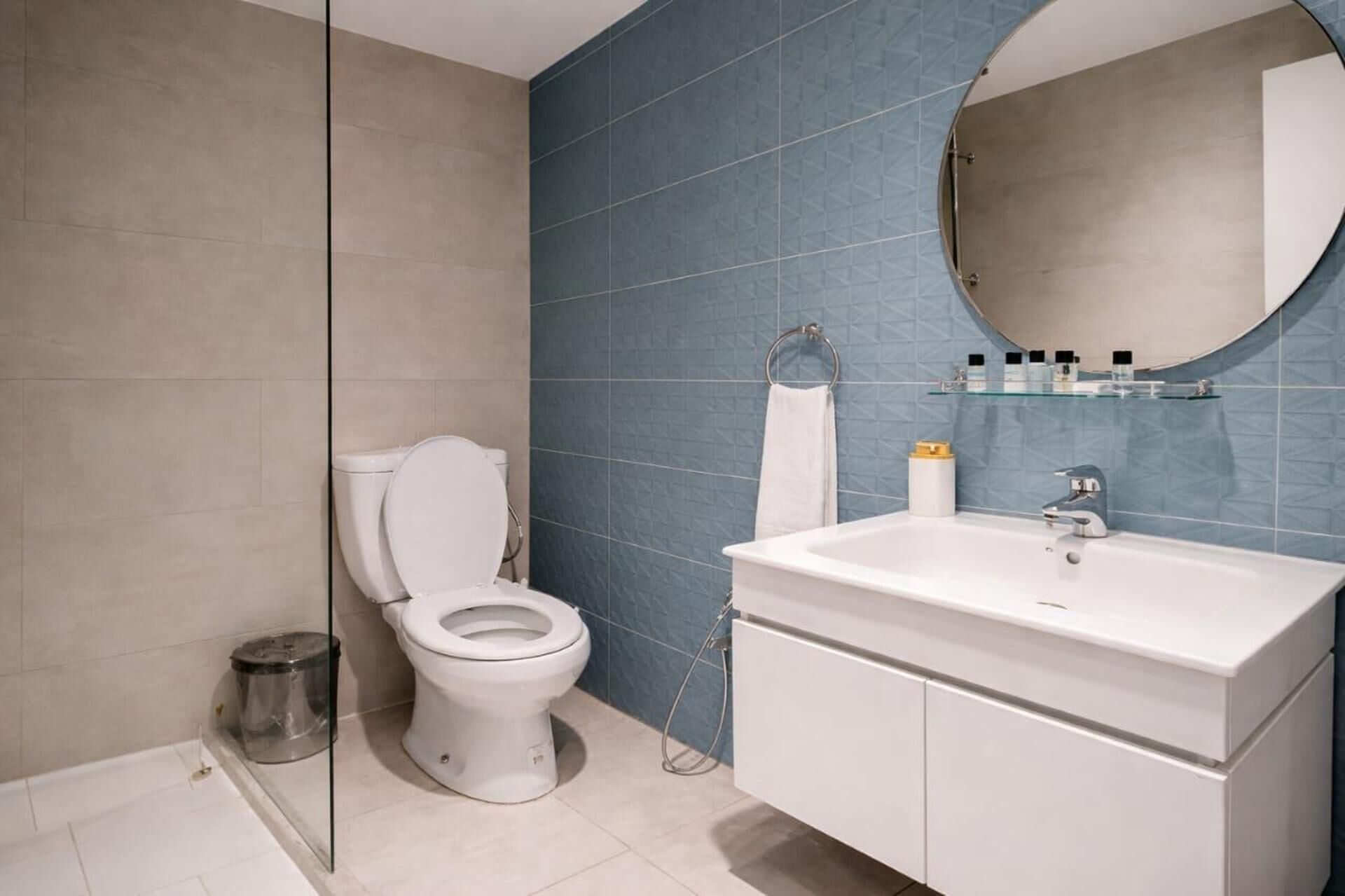 A bathroom with a toilet, sink, and mirror.