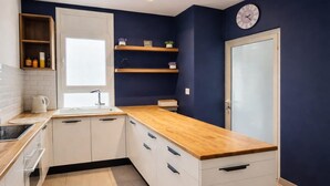 A compact kitchen with white cabinets, a wooden countertop, a window, and a clock on the wall. - Lovely 1-bed Apartment in Lac1 Tunis (Tunis)