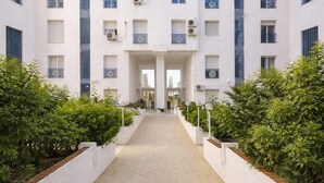 A multi-story building with a central entrance, air conditioning units, and a paved pathway flanked by greenery. - Lovely 1-bed Apartment in Lac1 Tunis (Tunis)