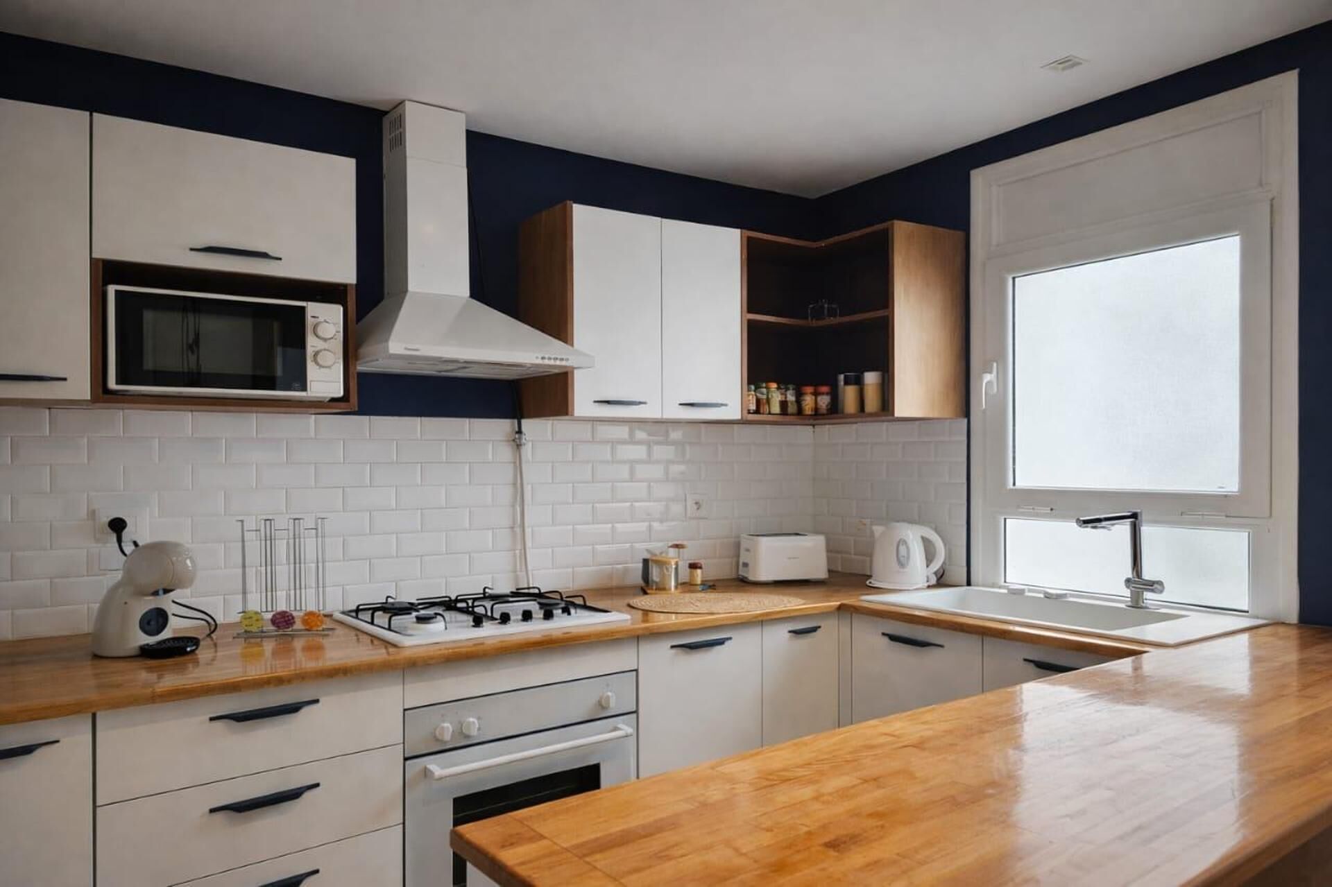 A modern kitchen with white cabinets, a gas stove, a microwave, and a window providing natural light.