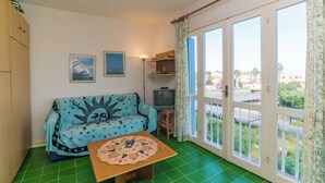 Un salon avec un canapé, une petite table, un téléviseur et une vue dégagée grâce à de grandes fenêtres.