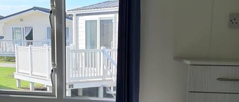 Un dormitorio con cama, cómoda, ventana y vistas a casas móviles, y un radiador.