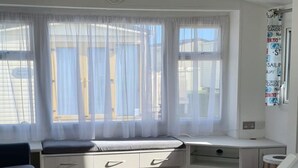 Una habitación moderna y luminosa con piso de madera, un sofá, una mesa de comedor y una zona de cocina con una silla roja.