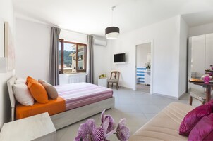 Un dormitorio moderno con cama, sofá, televisión y vistas al exterior.