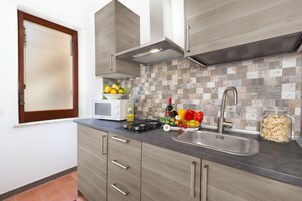 Una cocina moderna con gabinetes grises, un lavaplatos de acero inoxidable y un microondas.
