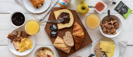Una mesa de desayuno con diferentes alimentos y acompañamientos.