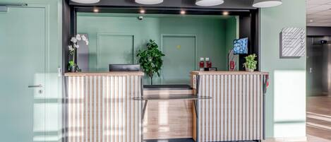 Un área de recepción con una pared verde, un mostrador de madera y un piso estampado.