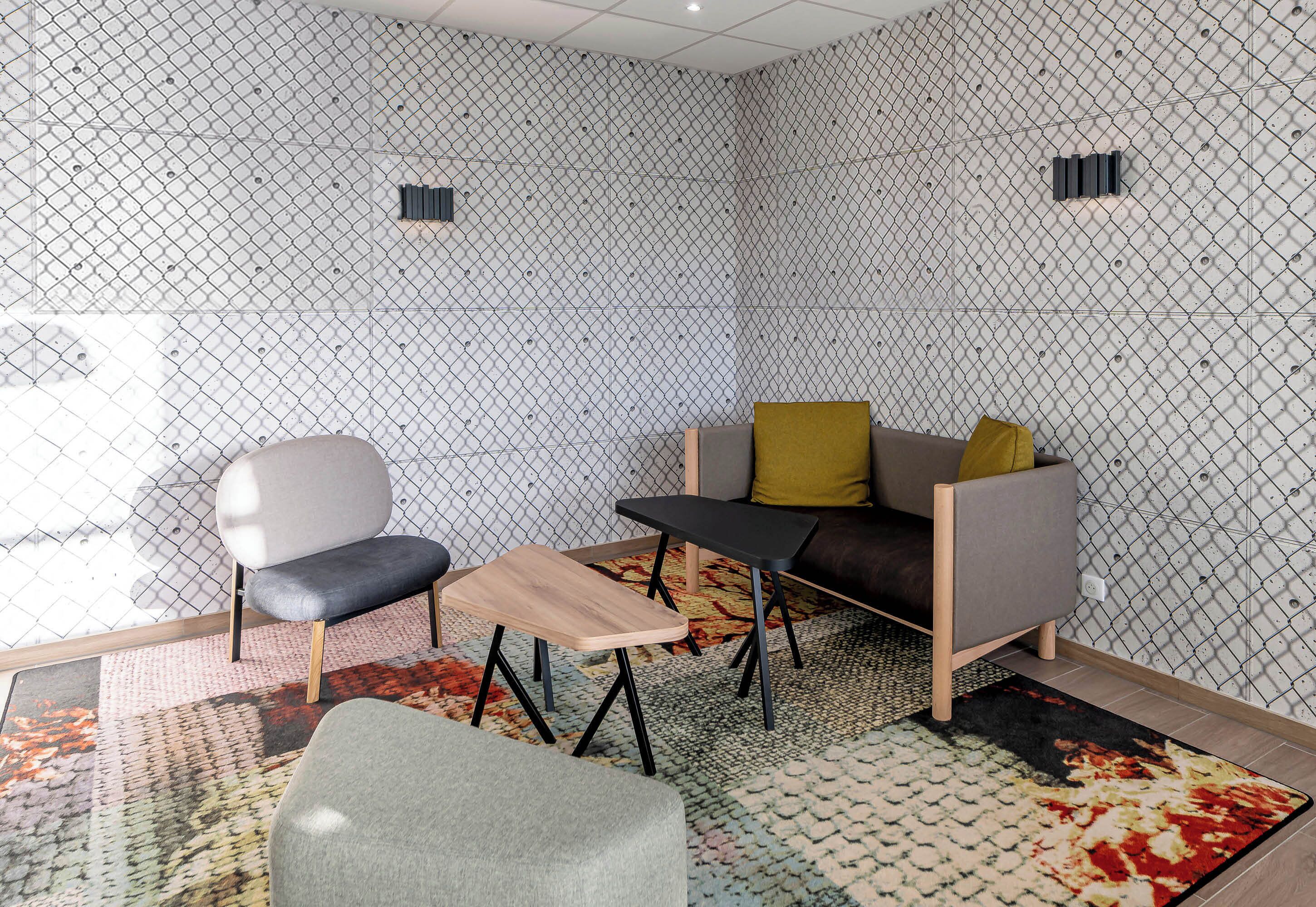 A modern room with a sofa, two chairs, a small table, and patterned walls.