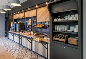 A modern breakfast bar with a variety of food items, a coffee machine, and neatly arranged dishes and utensils.
