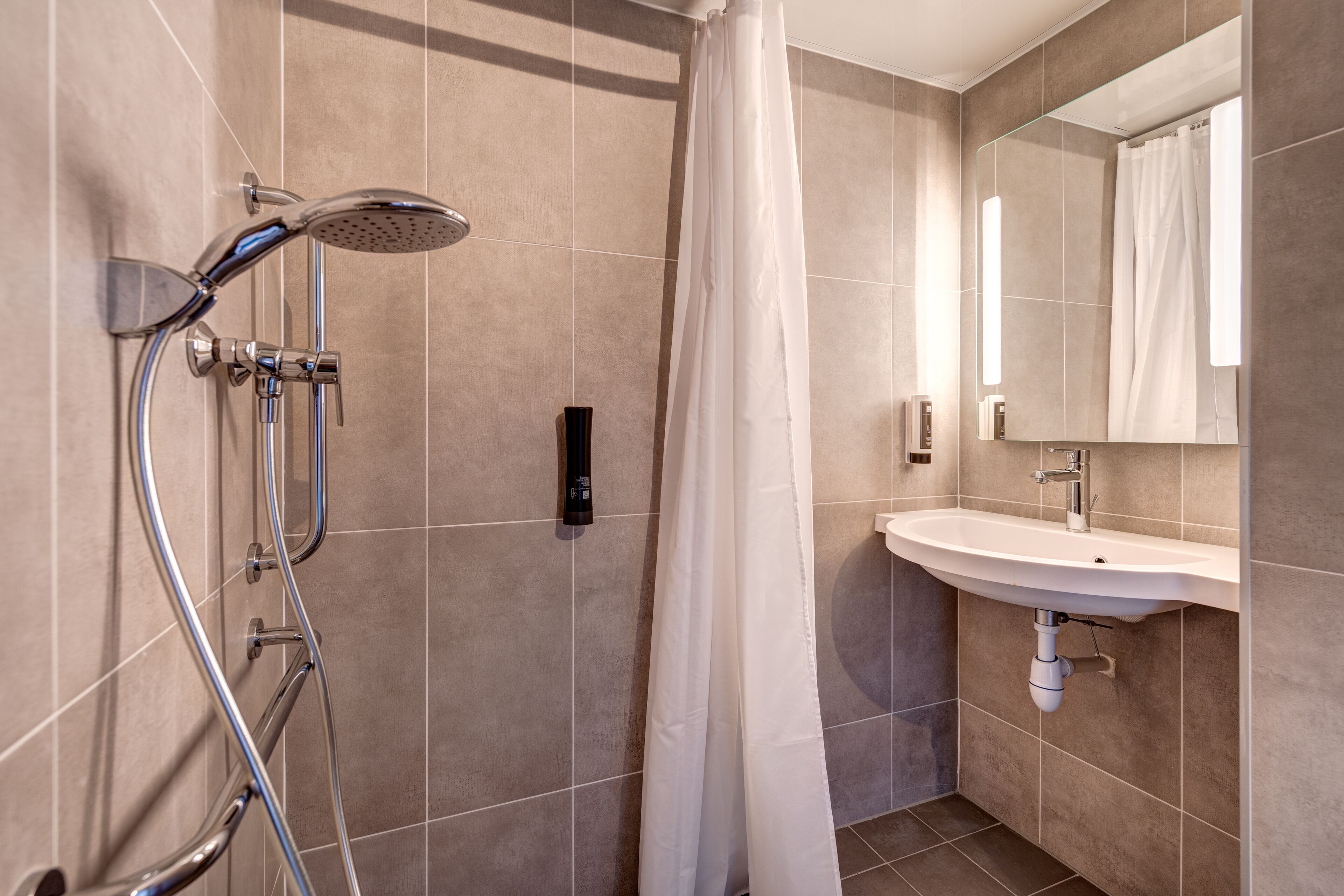 Ein modernes Badezimmer mit Dusche, Waschbecken und Spiegel.