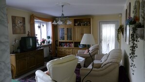 A living room with a sofa, armchairs, a television, a cabinet, and a lamp. - Apartment on the 1st floor. Only 10 minutes walk to the town center. (Berchtesgaden)