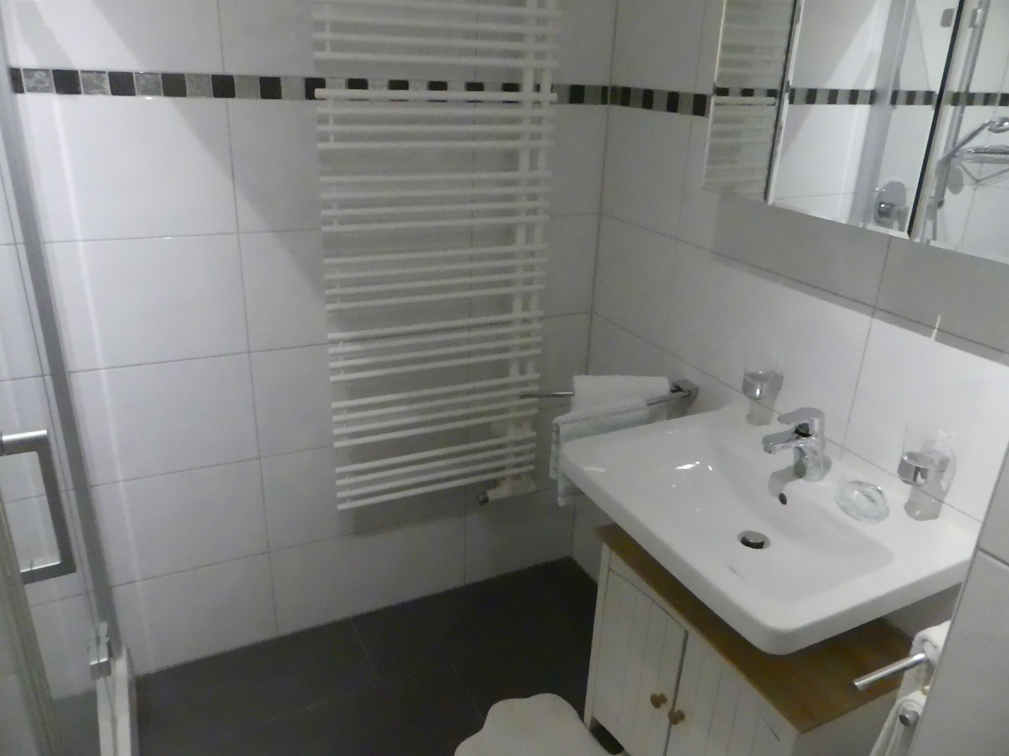 Une salle de bain avec un lavabo blanc, un miroir et un porte-serviettes.