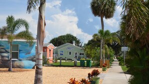 A beachfront property with a mural, a surf shop, and a pathway lined with palm trees.