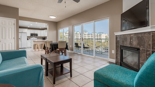 A spacious living room with teal sofas, a fireplace, and a TV.