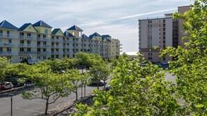 A hotel with multiple balconies, a parking lot, and a clear sky. - Princess Irene Unit 202 Oceanside 3BR 2BathCondo +Jacuzzi and parking (Ocean City)