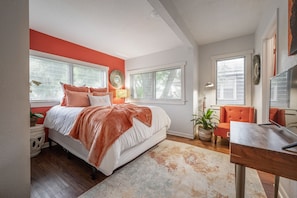 Quarto com cama, duas janelas, escrivaninha e cadeira.