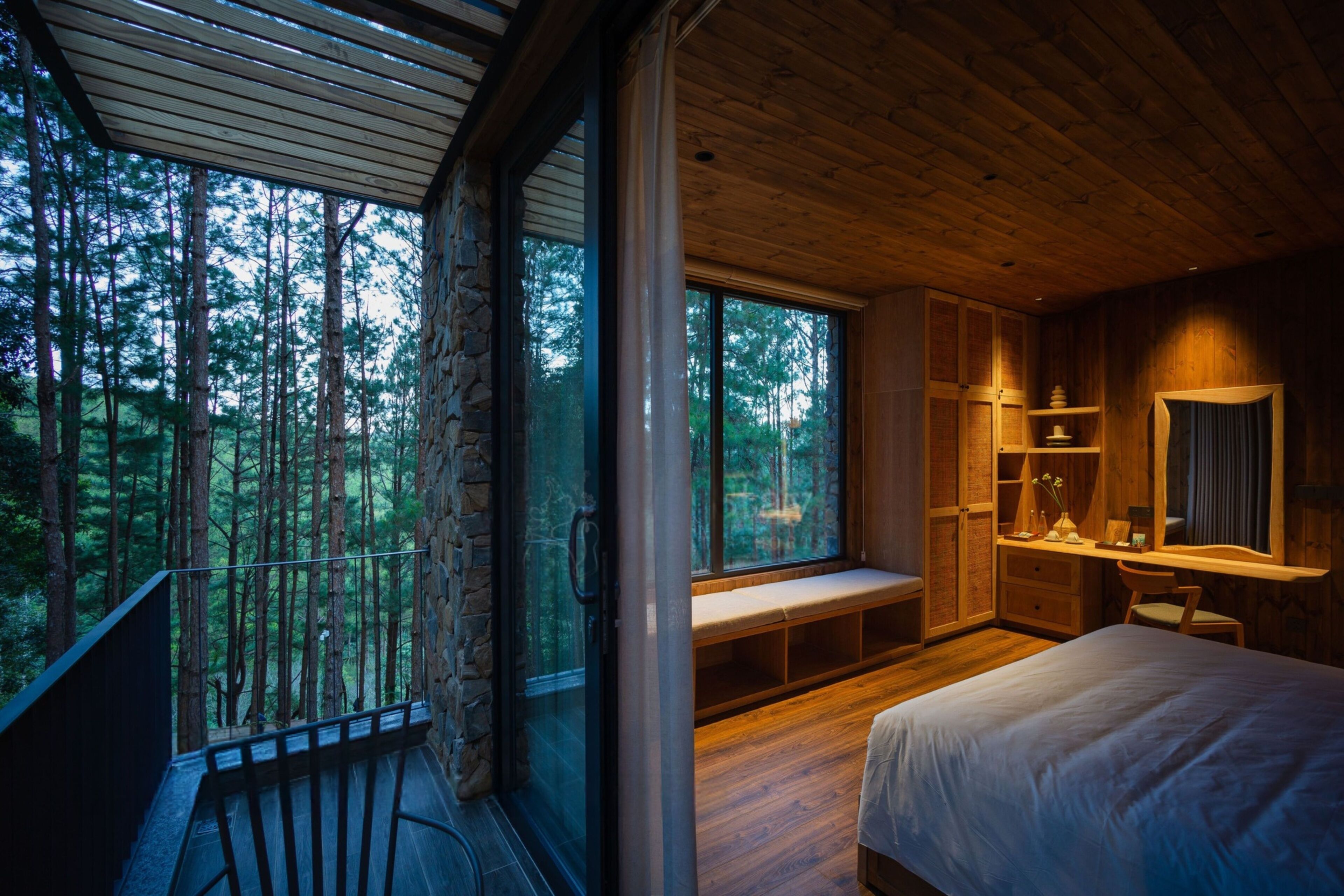 A bedroom with a large window, wooden ceiling, and a bed.