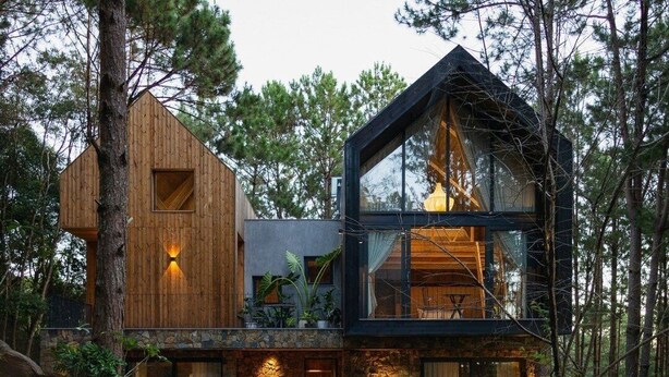 A modern two-story cabin with a wooden exterior and glass balcony, surrounded by trees. - Mơ Stay Forest Resort (Xuan Huong - Da Lat)