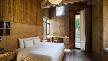 A wooden room with a large bed, a desk, and a window.