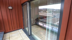 A balcony with a glass door, a metal railing, and a view of a cityscape. - Captivating 1-bed Apartment in London (London)