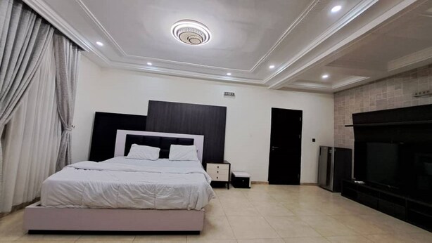 Un dormitorio moderno con una cama grande, un televisor y una chimenea.