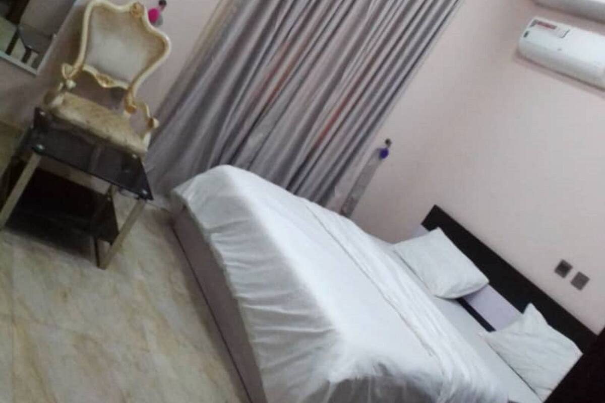 Quarto de hotel com cama, cadeira, escrivaninha e espelho.