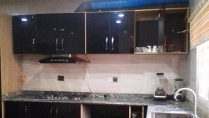 Una cocina con armarios oscuros, encimera de mármol y estufa empotrada.