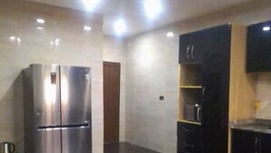 Una cocina moderna con un refrigerador de acero inoxidable, gabinetes negros y piso de baldosas.