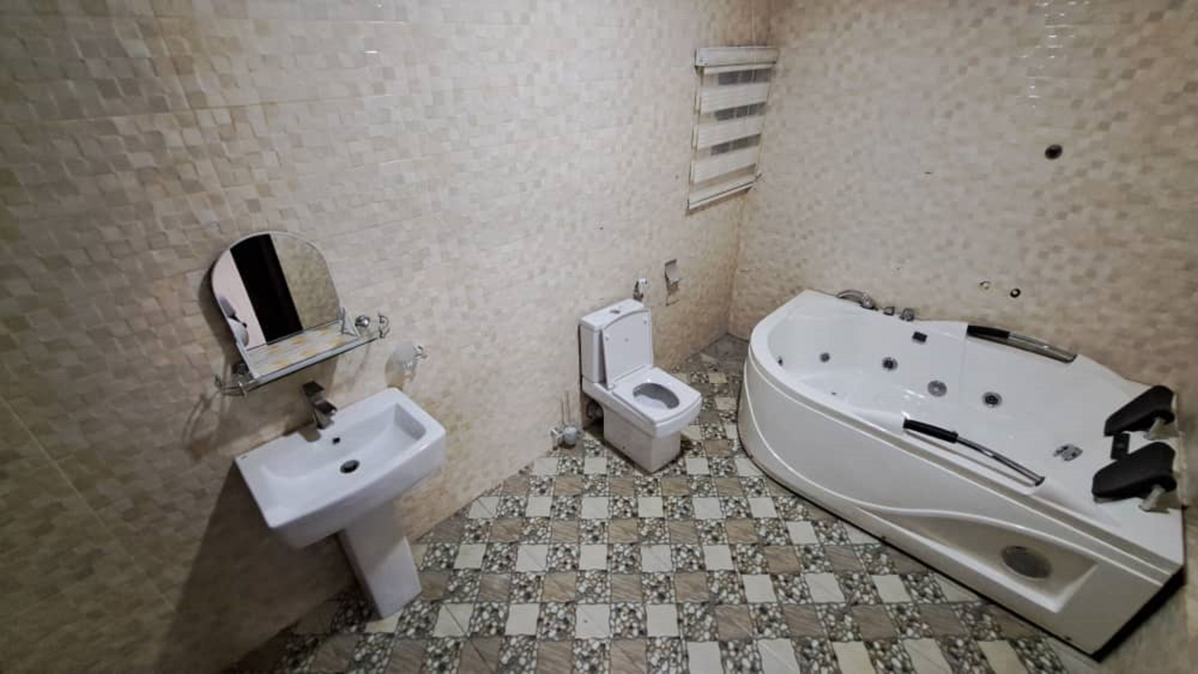 Un bany amb un lavabo, vàter i banyera hidromassatge.