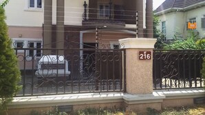 Una casa de dos pisos con un porche cubierto, un balcón y una entrada protegida por un portón.