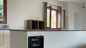 Ett modernt kök med ett inbyggt kylskåp, träskåp och ett fönster med gardiner.