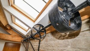 Une pièce avec un mur en pierre, une porte en bois et un plafond doté de lucarnes.
