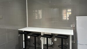 A modern kitchen with a white countertop and four black bar stools.