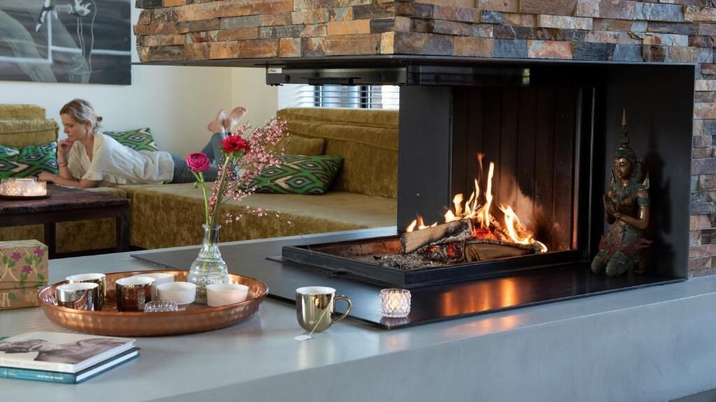 Una sala de estar moderna con chimenea, un sofá y una bandeja decorativa con velas y un florero.