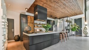 A modern kitchen with a central island, wooden ceiling, and minimalist decor. - het Lichthuis (Zandvoort)