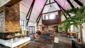 A spacious living area with a stone fireplace, modern seating, and a large plant. - het Lichthuis (Zandvoort)