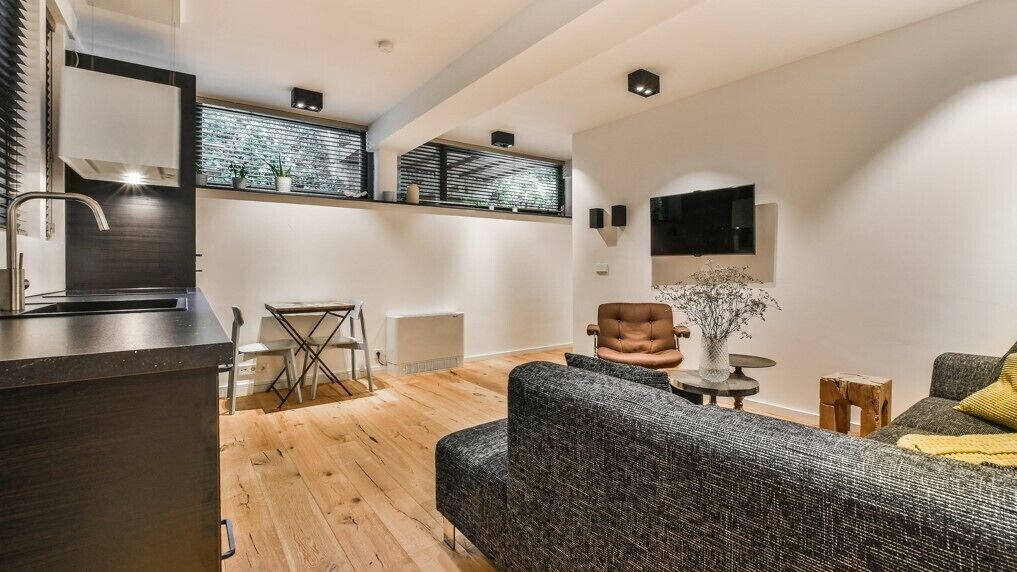 Un salon moderne avec un canapé, un fauteuil et une petite table sur laquelle est posé un vase.