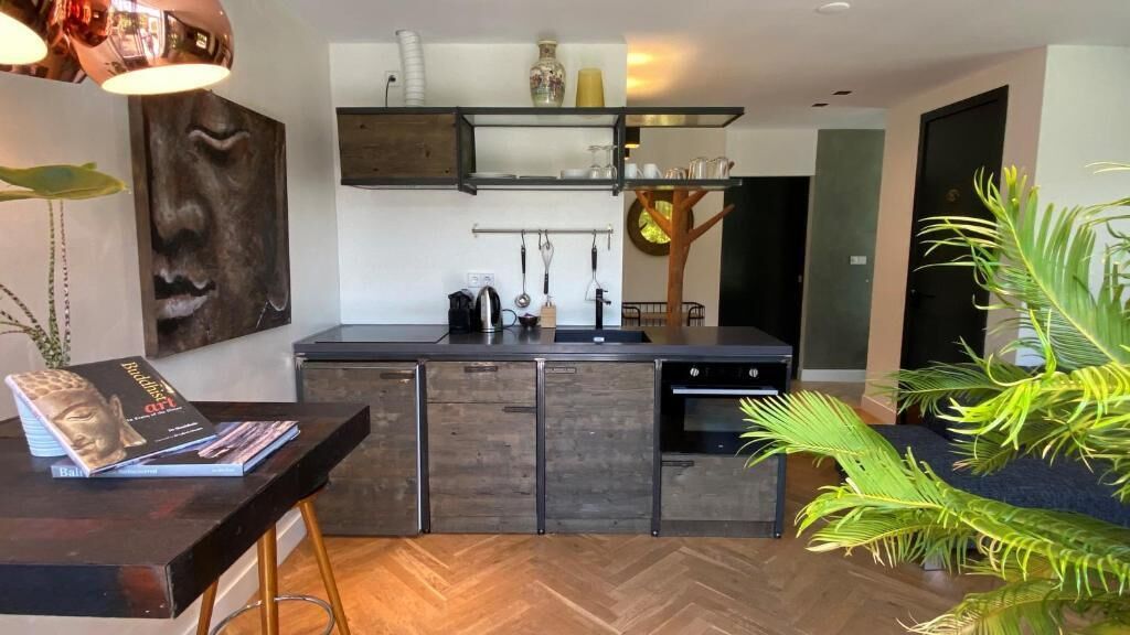A modern kitchen with dark cabinetry, a wooden herringbone floor, and a central island.