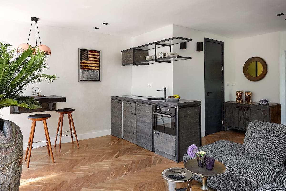 Uma cozinha moderna com uma ilha central, banquetas e uma área de refeições com sofá.