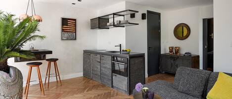 A modern kitchen with a central island, bar stools, and a dining area with a sofa.