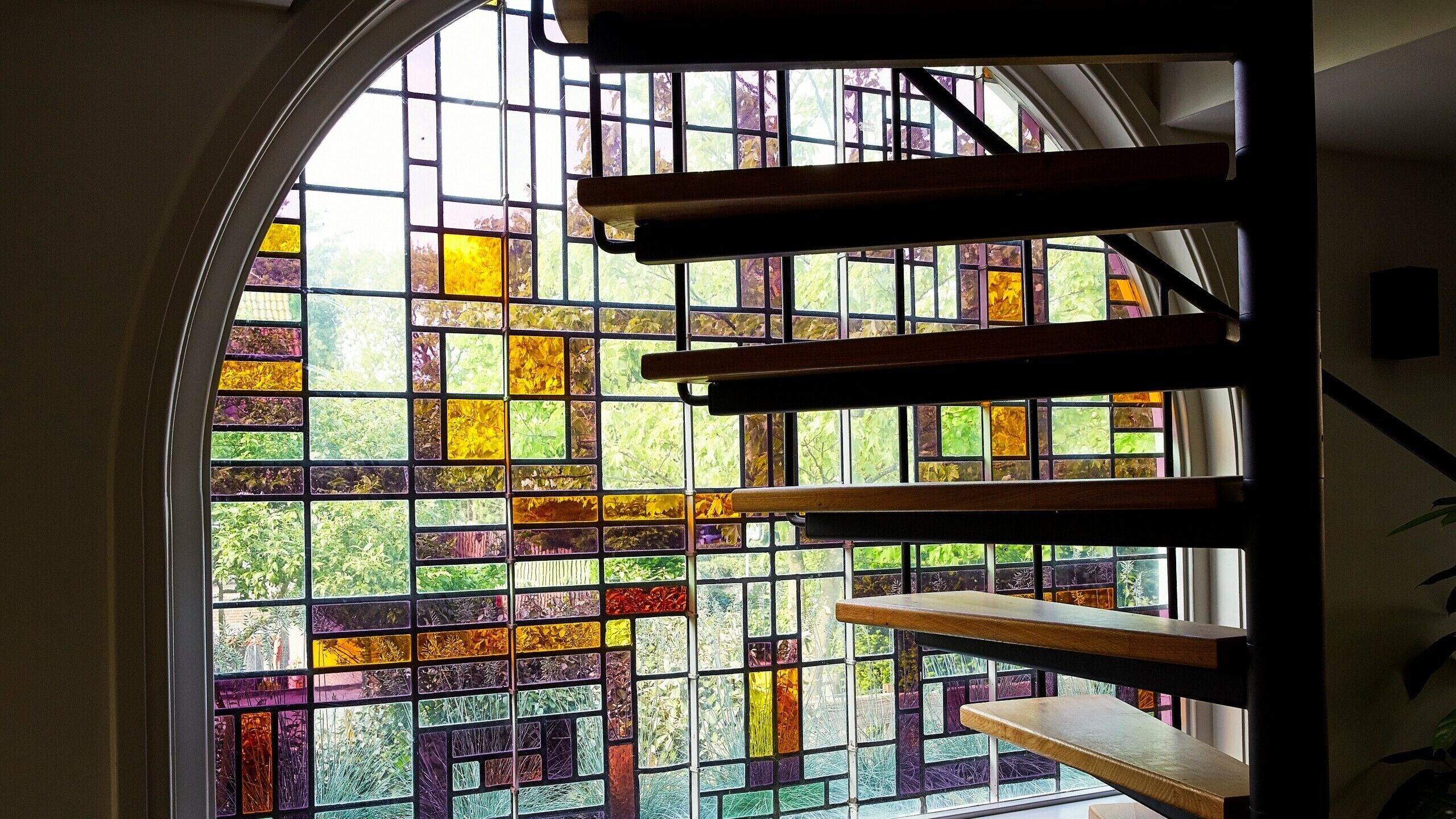 A staircase with wooden steps and a stained glass window behind it.