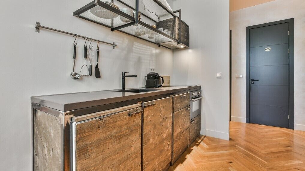 Una cocina con un armario de madera, encimera de acero inoxidable y una cafetera.