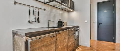 Una cocina con un armario de madera, encimera de acero inoxidable y una cafetera.
